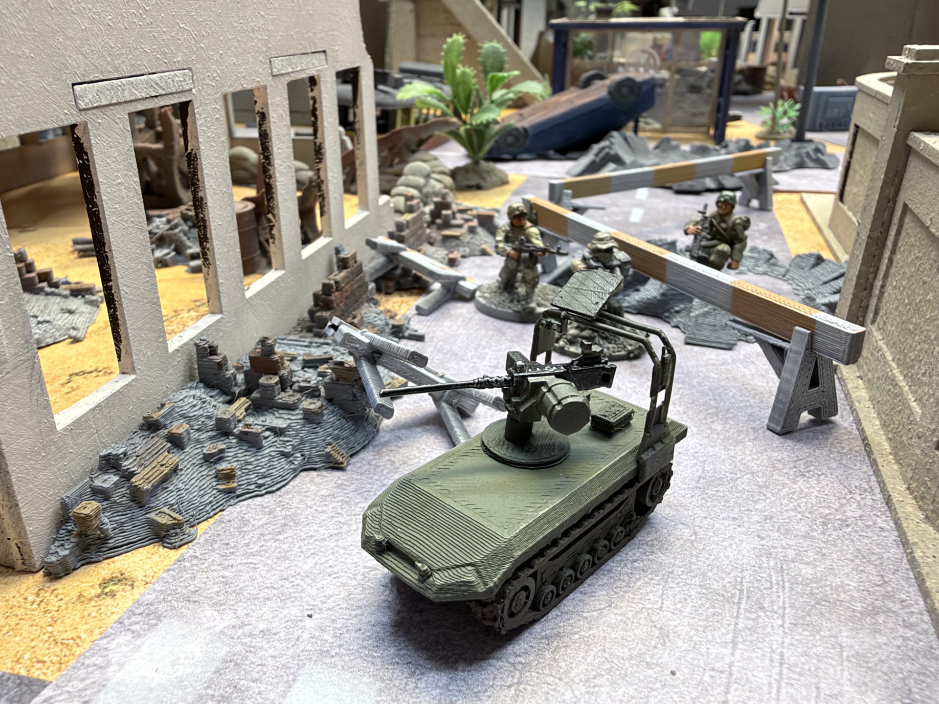 An armed tracked UGV with a machine-gun weapon station advancing along a barricaded street