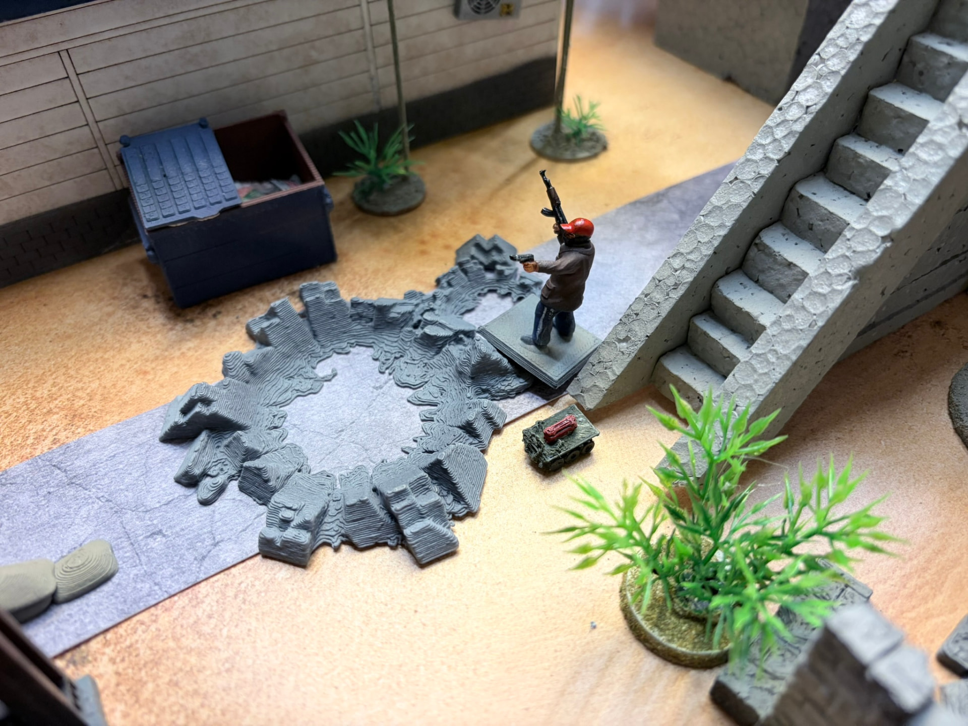 A tracked micro-UGV carrying an explosive block near a staircase beside a blast crater