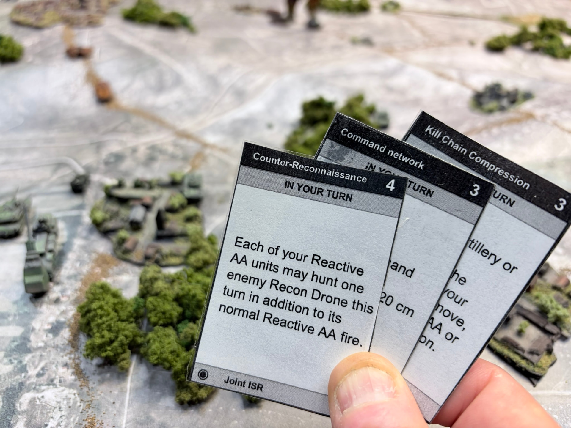 A player's hand of three sleeved Combat Enabler cards