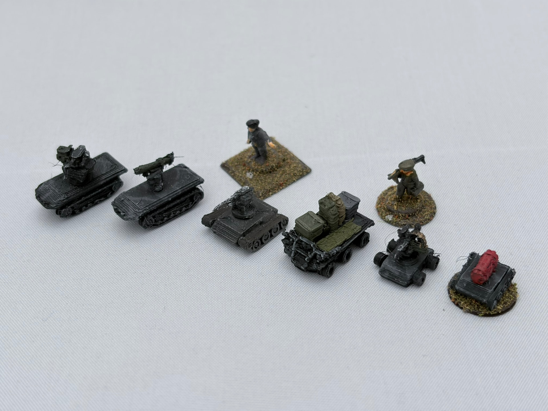 Printed tracked and wheeled ground drones beside 10 mm miniature figures
