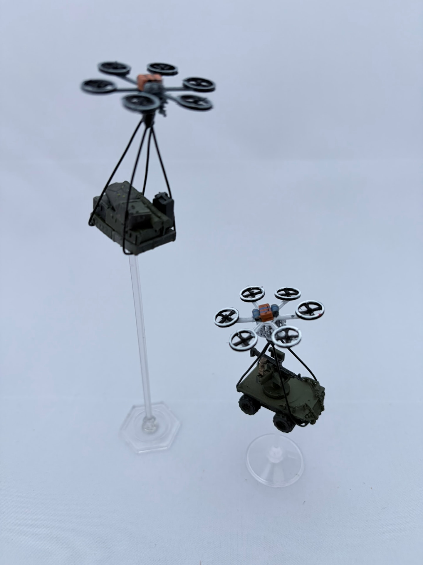 Two printed heavy-lift hexacopters on flight stands carrying ground drones underneath