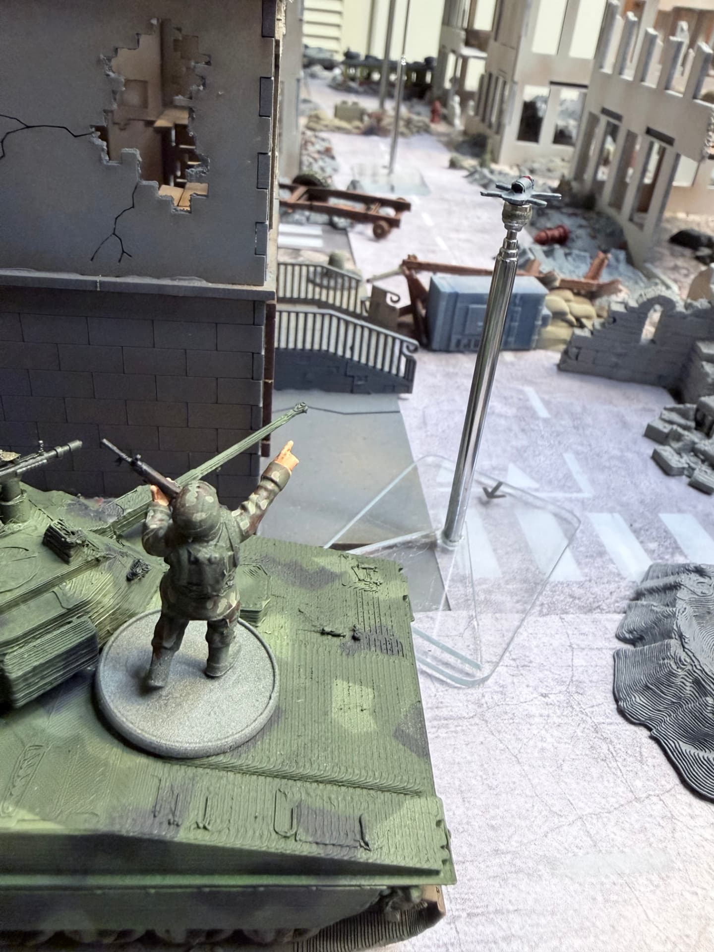 A soldier standing on an armoured vehicle pointing at a small winged drone on a flight stand